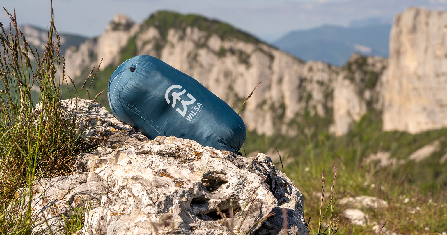 sac de couchage duvet wilsa bleu dans un décor montagne